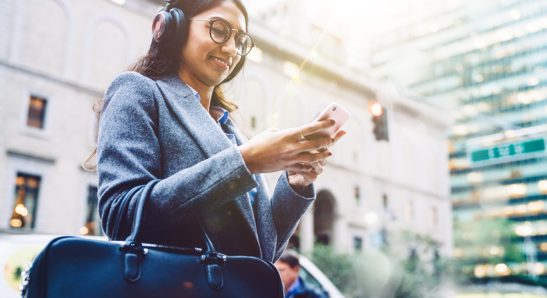 woman with earphones holding smartphone
