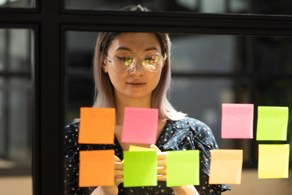 Woman putting sticky notes on the glass wall.