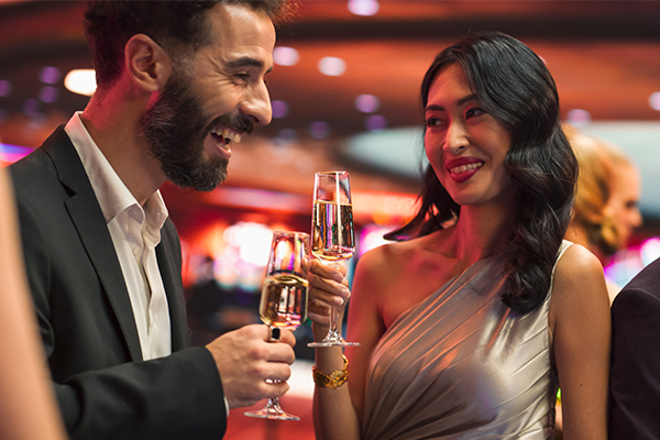 Dressed Up Couple Holding Drinks In A Busy Casio